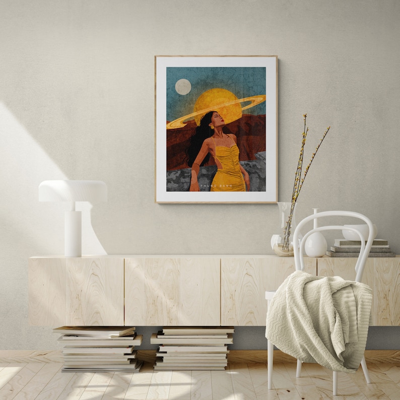 May include: A digital art print featuring a woman with a ring of planets around her head, standing in a desert landscape with a yellow sun and a white moon in the sky.