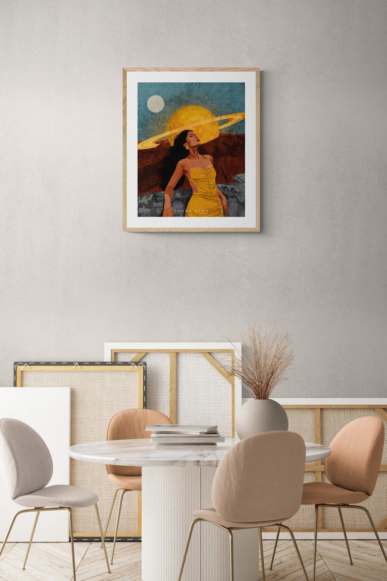 May include: A framed illustration of a woman in a yellow dress standing in a desert landscape with a large yellow sun and a ring around it in the sky. The text "SAKURA SATOH" is at the bottom of the image.