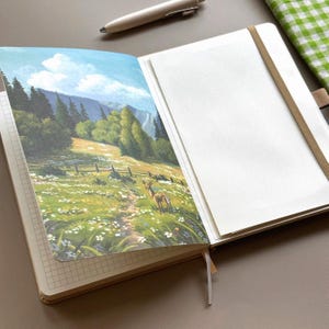 May include: Open notebook with a landscape painting of a deer in a meadow. The painting features a path, fence, and trees under a blue sky. The notebook has a grid pattern on the left page and blank pages on the right. A pen rests above the notebook.