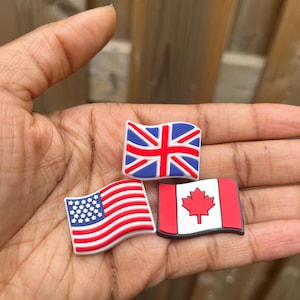 May include: Three small plastic flags, representing the United Kingdom, the United States, and Canada. The flags are red, white, and blue.
