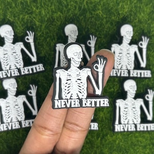 May include: Multiple black and white skeleton hand stickers with the text "NEVER BETTER" on each. The stickers are on a green background.