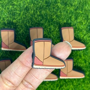 May include: A set of six brown and pink boot charms. The charms are made of rubber and have a detailed design.