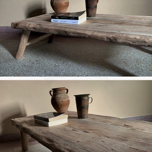 K&ouml;nnte beinhalten: Ein rustikaler Couchtisch aus Holz mit nat&uuml;rlicher Kante. Er zeigt zwei Terrakotta-Vasen, einen Holzbecher und zwei B&uuml;cher. Der Tisch hat schr&auml;ge Beine und das Holz hat eine hellbraune Farbe. Der Tisch ist etwa 150 cm lang.
