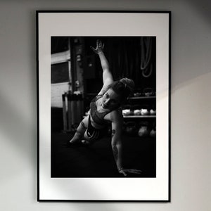 May include: Black and white photo of a person doing a push-up exercise in a gym setting.