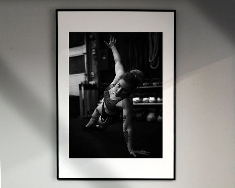 May include: Black and white photo of a person doing a push-up exercise in a gym setting.