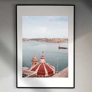 May include: A framed photograph of a red and white domed building with a view of a body of water and a small boat in the distance.