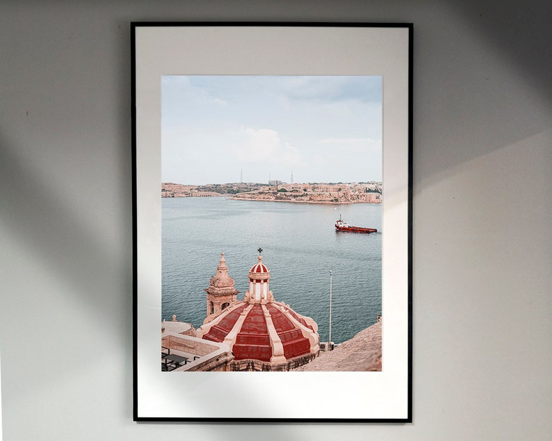 May include: A framed photograph of a red and white domed building with a view of a body of water and a small boat in the distance.
