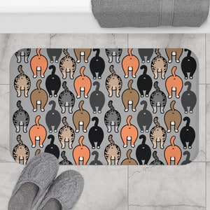May include: A gray bath mat with a repeating pattern of cat butts in various colors, including orange, brown, gray, and black.