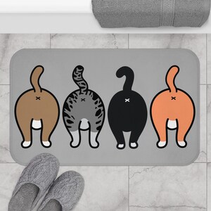 Può includere: Un tappetino da bagno grigio con quattro gatti di cartone animati che guardano lontano dallo spettatore. I gatti sono marroni, grigi, neri e arancioni. Ogni gatto ha una coda bianca e una macchia bianca sul sedere.