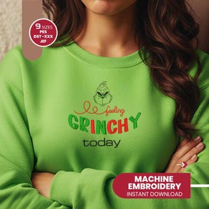 May include: A lime green sweatshirt with the phrase "feeling GRINCHY today" embroidered in red and green. The design includes a Grinch face. The sweatshirt also has a red banner that says "MACHINE EMBROIDERY INSTANT DOWNLOAD".