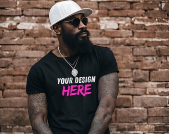 Puede incluir: Un hombre con una camiseta negra con el texto "YOUR DESIGN HERE" en letras rosas. Lleva una gorra de béisbol blanca y gafas de sol. Tiene barba y tatuajes en los brazos.