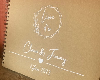May include: A brown, spiral-bound guest book with the text "Livre d'or" in a white geometric frame, followed by "Clara & Jimmy" and "11 Juin 2022" in white cursive script.