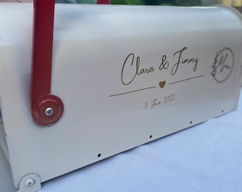 May include: White mailbox with a red flag, decorated with gold lettering that reads "Clara & Jimmy" and "11 June 2022".
