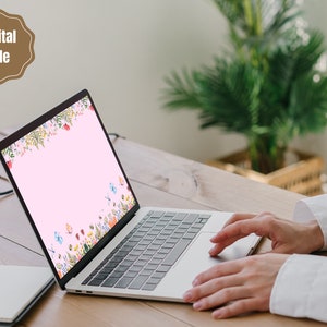 May include: A laptop computer with a pink background and a floral design with butterflies. The laptop is open and the screen is visible. The laptop is on a wooden table.