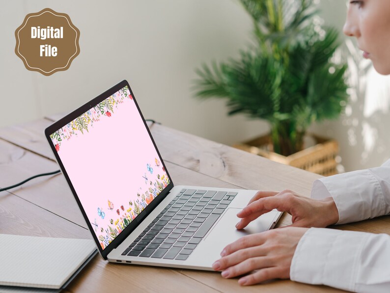 May include: A laptop computer with a pink background and a floral design with butterflies. The laptop is open and the screen is visible. The laptop is on a wooden table.
