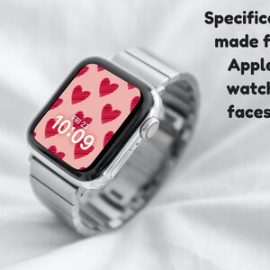 May include: A silver Apple Watch with a pink watch face featuring a pattern of red hearts. The watch face displays the time as 10:09 and the date as FRI 23.
