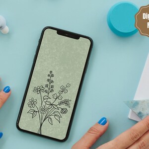 以下が含まれることがあります： 緑色の背景に花束のデジタルイラストが表示されたスマートフォン。花は白黒の線画です。スマートフォンは薄い青色の表面の上に置かれています。