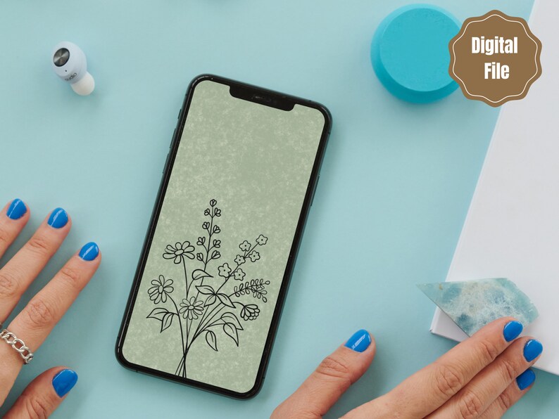 以下が含まれることがあります： 緑色の背景に花束のデジタルイラストが表示されたスマートフォン。花は白黒の線画です。スマートフォンは薄い青色の表面の上に置かれています。