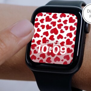 May include: A black Apple Watch with a white background and red hearts pattern. The time is 10:09 and the day is Friday the 23rd.