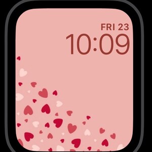 May include: A pink Apple Watch face with a digital clock displaying "FRI 23 10:09" and a pattern of pink and white hearts in the lower left corner.