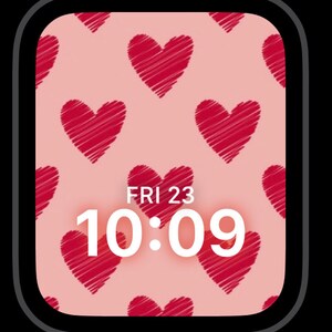 May include: A pink watch face with a pattern of red hearts. The time is 10:09 and the date is FRI 23.