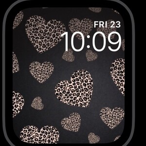 K&ouml;nnte beinhalten: Ein schwarzes Apple Watch-Zifferblatt mit einem Leopardenmuster-Herz-Muster und der angezeigten Uhrzeit 10:09. Das Datum ist FRI 23.
