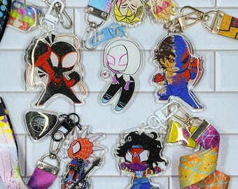 May include: Eight colorful cartoon character keychains with different designs. Each keychain features a different character with a unique pose and expression. The keychains are attached to colorful lanyards with geometric patterns.