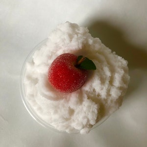 May include: White fluffy slime with a red apple on top in a clear plastic container.