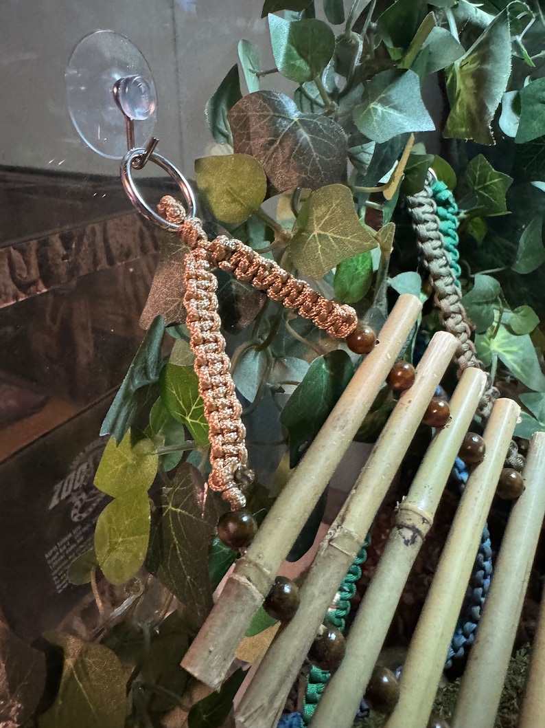 Puede incluir: Un juguete para p&aacute;jaros de bamb&uacute; natural con cuerdas de colores y cuentas de madera. El juguete est&aacute; unido a una ventosa para colgarlo f&aacute;cilmente.
