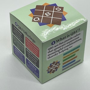 May include: A green cube with a brown and blue design on the top. The cube has the text "QB5 Offerings" on one side and "What is QB5?" on another side. The text on the cube describes the benefits of using QB5, such as improving imagination, developing STEM skills, and generating ideas.