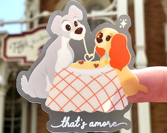 May include: A sticker featuring Lady and the Tramp sharing a plate of spaghetti with the text "that's amore".
