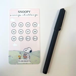 Könnte beinhalten: Eine rosa und weiße Karte mit dem Text "SNOOPY savings challenge" oben. Die Karte hat ein Raster mit 12 Kreisen, in denen die Zahlen 1 bis 12 stehen. Die Karte zeigt auch ein Cartoon-Bild von Snoopy und Woodstock. Der Text "TS BUDGETS" befindet sich unten auf der Karte.