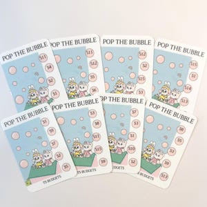 May include: A collection of rectangular cards with a light blue background and pink bubble graphics. Each card features the text "POP THE BUBBLE" and illustrations of cartoon bunnies. The cards are labeled with dollar amounts and the text "TS BUDGETS".