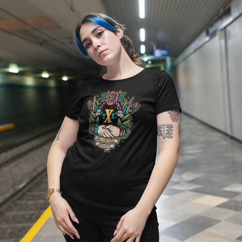May include: A black t-shirt with a colorful graphic design featuring two hands clasped together with a rose and birds. The text on the graphic reads "Straight Edge Afterlife".