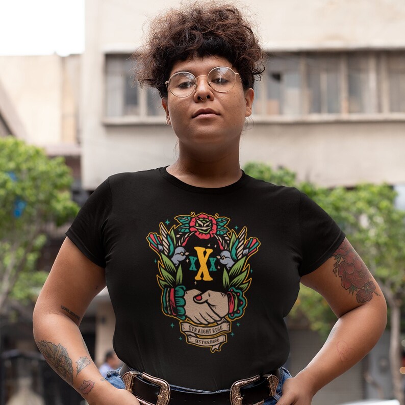 May include: Black t-shirt with a colorful graphic design featuring a handshake, two birds, and a rose. The graphic also includes the text "Straight Edge" and "Betterhood".