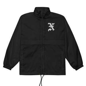 May include: Black windbreaker jacket featuring a white gothic letter "A" on the chest. The jacket has a full zip, a stand-up collar, and a drawstring hem. The sleeves are long and the jacket appears to be made of a lightweight material.