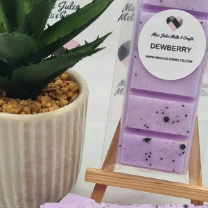 May include: Purple wax melt bar with black glitter and the text "DEWBERRY" and "www.MISSJULESMELTS.COM".