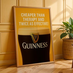 Może przedstawiać: Oprawiony plakat Guinness z kuflem stoutu, z logo marki i napisem "CHEAPER THAN THERAPY AND TWICE AS EFFECTIVE!". Plakat jest prezentowany na ż&oacute;łtym tle, z drewnianą ramą.