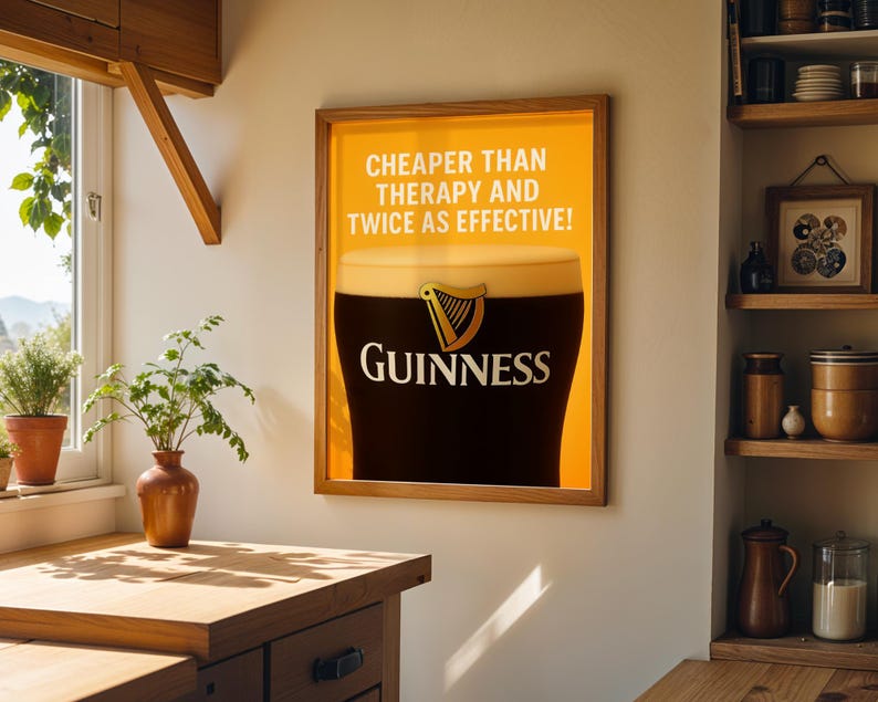 Może przedstawiać: Oprawiona reklama Guinnessa z napisem "Tańsze niż terapia i dwa razy skuteczniejsze!" Obraz przedstawia kufel Guinnessa z logo marki. Rama jest w kolorze drewna, a tło to kuchnia.