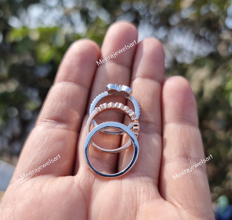 May include: A stack of three rings featuring a silver-toned band with a decorative top, a rose gold-toned band with a scalloped edge, and a plain silver-toned band. The text Meerajewelsart is visible in the image.