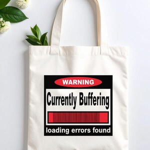 K&ouml;nnte beinhalten: Eine wei&szlig;e Stofftasche mit einer rechteckigen Grafik, die ein rotes Oval mit dem Wort WARNING, den schwarzen Text Currently Buffering, einen roten Ladebalken und den Text loading errors found am unteren Rand enth&auml;lt.