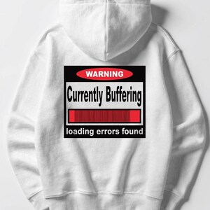 K&ouml;nnte beinhalten: Ein wei&szlig;er Kapuzenpullover mit einem Grafikdruck auf der R&uuml;ckseite. Die Grafik besteht aus einem schwarzen Quadrat mit einem roten Oval, das das Wort WARNING enth&auml;lt. Darunter steht Currently Buffering, ein roter Ladebalken und loading errors found.