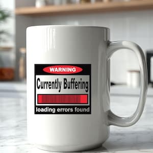 K&ouml;nnte beinhalten: Ein wei&szlig;er Keramikbecher mit einer rechteckigen Grafik, die ein rotes Oval mit dem Wort WARNING, den Text Currently Buffering, einen roten Ladebalken sowie den Text loading errors found in schwarzer und wei&szlig;er Schrift auf der Vorderseite zeigt.