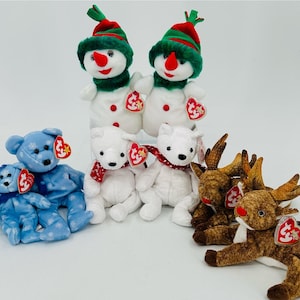 Puede incluir: Una colección de siete peluches, incluyendo dos muñecos de nieve, dos osos polares, un reno y dos osos azules. Los muñecos de nieve llevan sombreros y bufandas verdes, los osos polares tienen bufandas rojas y el reno tiene cuernos marrones. Todos los juguetes tienen etiquetas de Beanie Baby rojas y blancas.