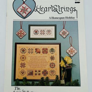 May include: A book cover for a cross-stitch pattern collection called "HeartStrings: A Homespun Holiday" by Pat Thode. The cover features a heart-shaped frame with a red, white, and green star design. The book title is written in a decorative font.