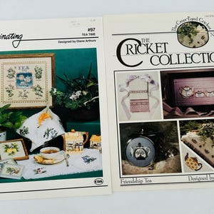 Könnte beinhalten: Zwei Kreuzstichmuster für Stickprojekte zum Thema Tee. Das erste Muster, "Tea Time", zeigt eine Teekanne und verschiedene Teekräuter. Das zweite Muster, "Friendship Tea", zeigt eine Teekanne und eine Teetasse auf einem Tablett.