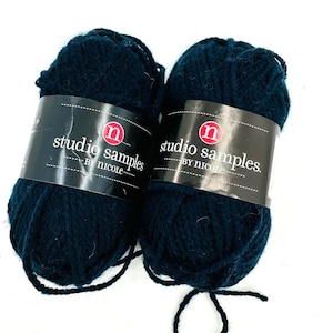 May include: Two balls of dark teal yarn with black labels. The labels read "studio samples" and "BY NICOLE" in white text. The yarn is thick and appears soft, suitable for knitting or crochet projects.