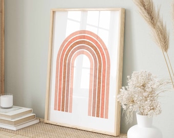 May include: A framed print of a rainbow with a peach, pink, and orange color scheme. The rainbow is centered on a white background. The frame is a light wood color.