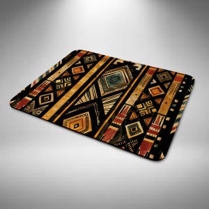May include: Rectangular mat with an abstract geometric pattern in black, gold, red, and blue. The design features diagonal stripes and various shapes, including diamonds and rectangles. The mat has a soft, textured appearance.
