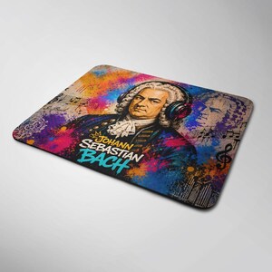 May include: A rectangular mouse pad featuring a portrait of Johann Sebastian Bach wearing modern headphones. The design includes vibrant splashes of orange, pink, and blue paint, musical notes, and the text Johann Sebastian Bach in bold letters.